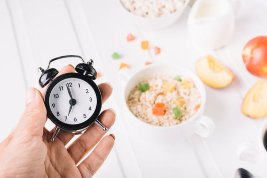 Alarm clock beside breakfast illustrating meal timing for muscle growth